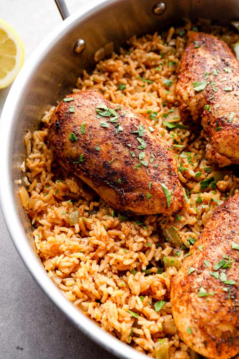 cajun chicken breasts on top of rice in a skillet