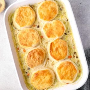 chicken pot pie casserole topped with biscuits in a white baking dish after baking