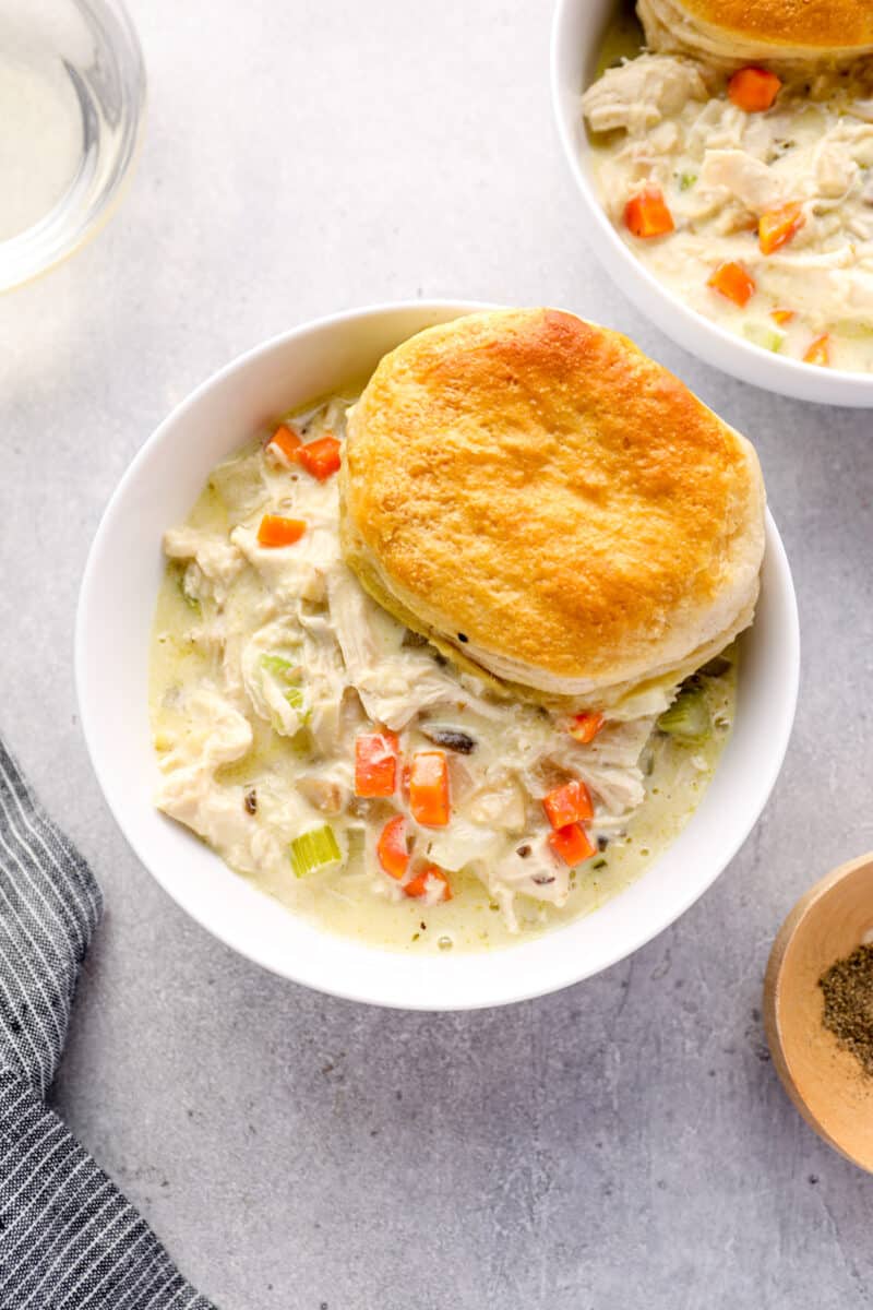 chicken pot pie casserole with a biscuit in a white bowl