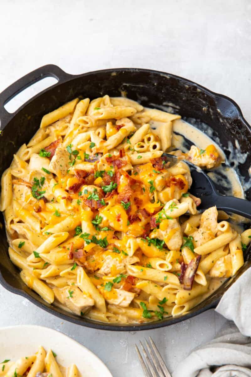 crack chicken pasta in a skillet with a serving spoon