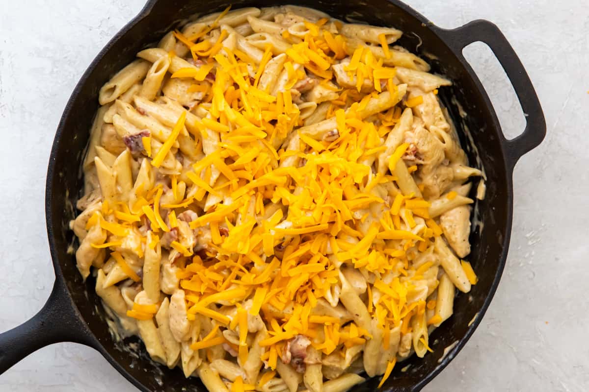 A skillet of crack chicken pasta topped with melted cheese.