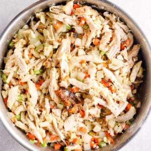 shredded chicken added to chopped vegetable filling in a pan
