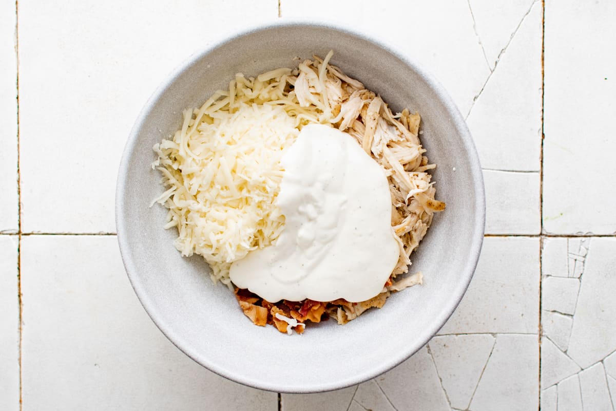 Cheese, chicken, bacon, and ranch dressing in a large bowl.