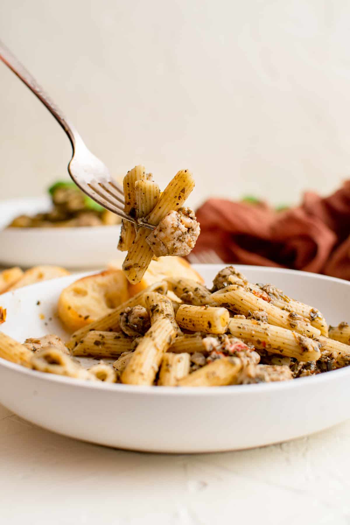 chicken pesto pasta in a white bowl with a serving on a fork