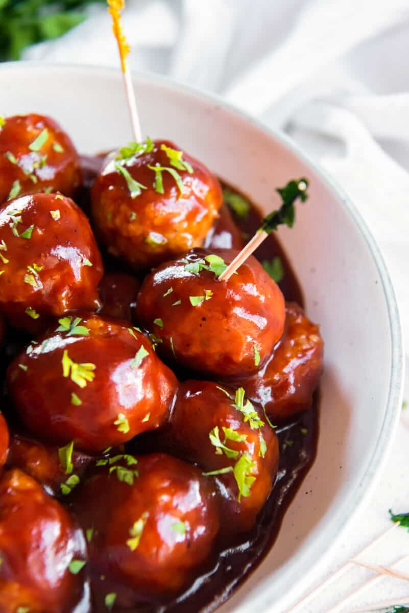 bbq chicken meatballs in a white serving bowl with toothpicks in them