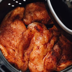 seasoned chicken breasts in an air fryer basket before cooking