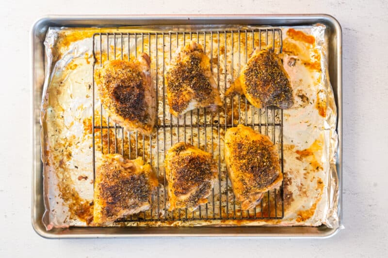 baked chicken thighs on a rack on top of a baking sheet