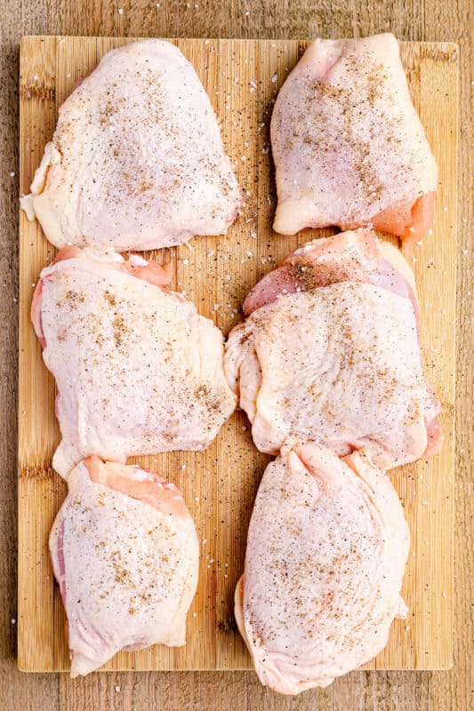 seasoned raw chicken thighs on a cutting board