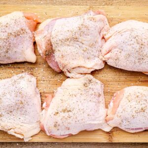 seasoned raw chicken thighs on a cutting board