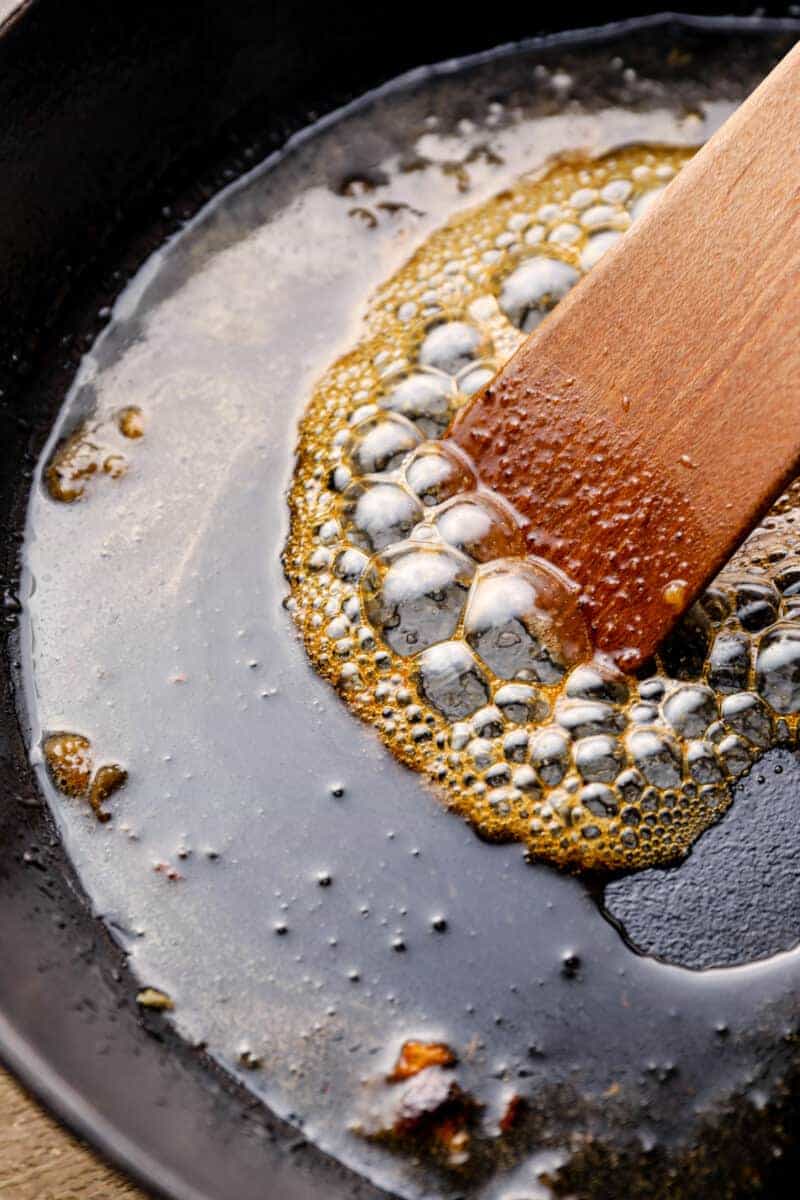 caramel chicken sauce in a skillet with a wood spoon