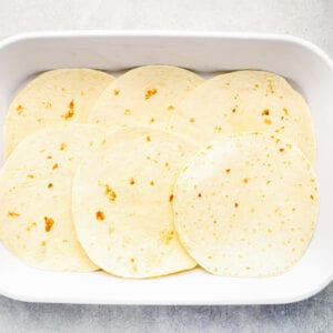tortillas in the bottom of a white baking dish