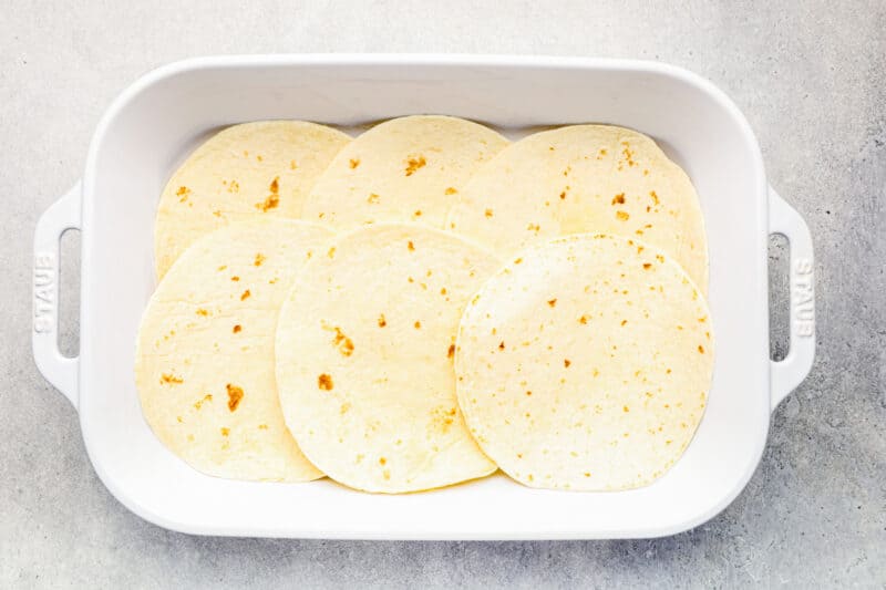 tortillas in the bottom of a white baking dish