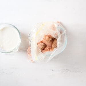 seasoned chicken tenders in a zip-top bag next to a bowl of buttermilk