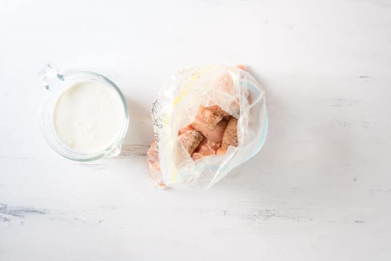 seasoned chicken tenders in a zip-top bag next to a bowl of buttermilk