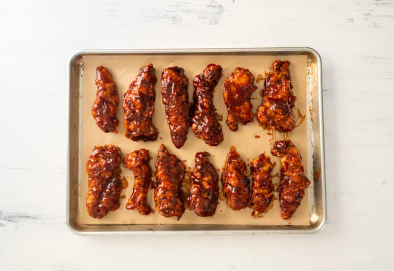 honey bbq chicken tenders on a parchment paper lined baking sheet