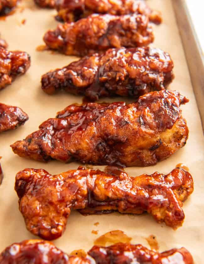 honey bbq chicken tenders on a parchment paper lined baking sheet