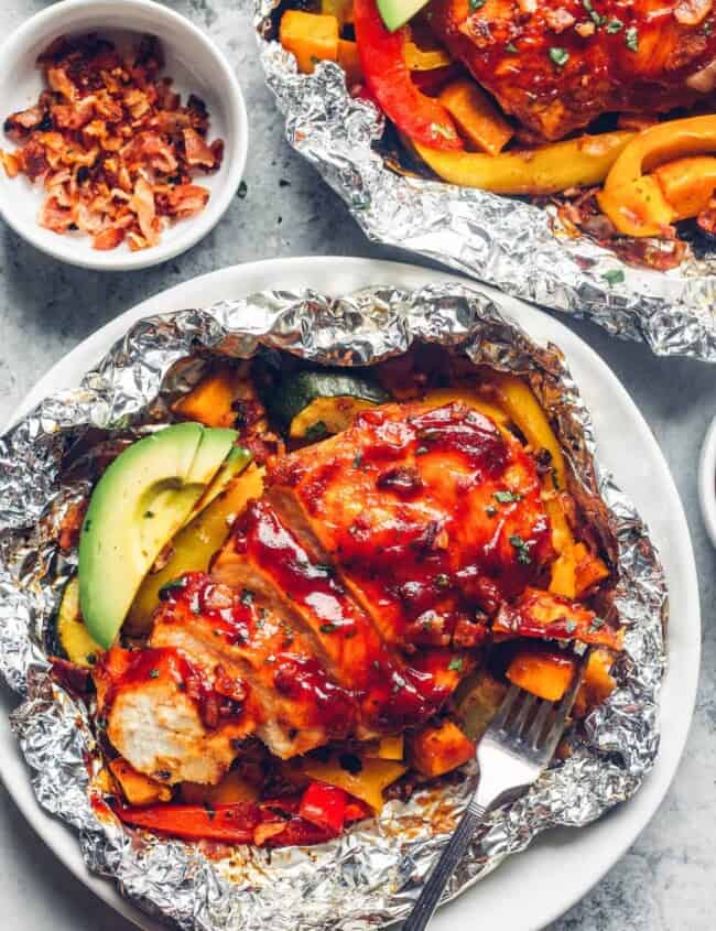 bbq chicken foil packet on a white plate with a fork.