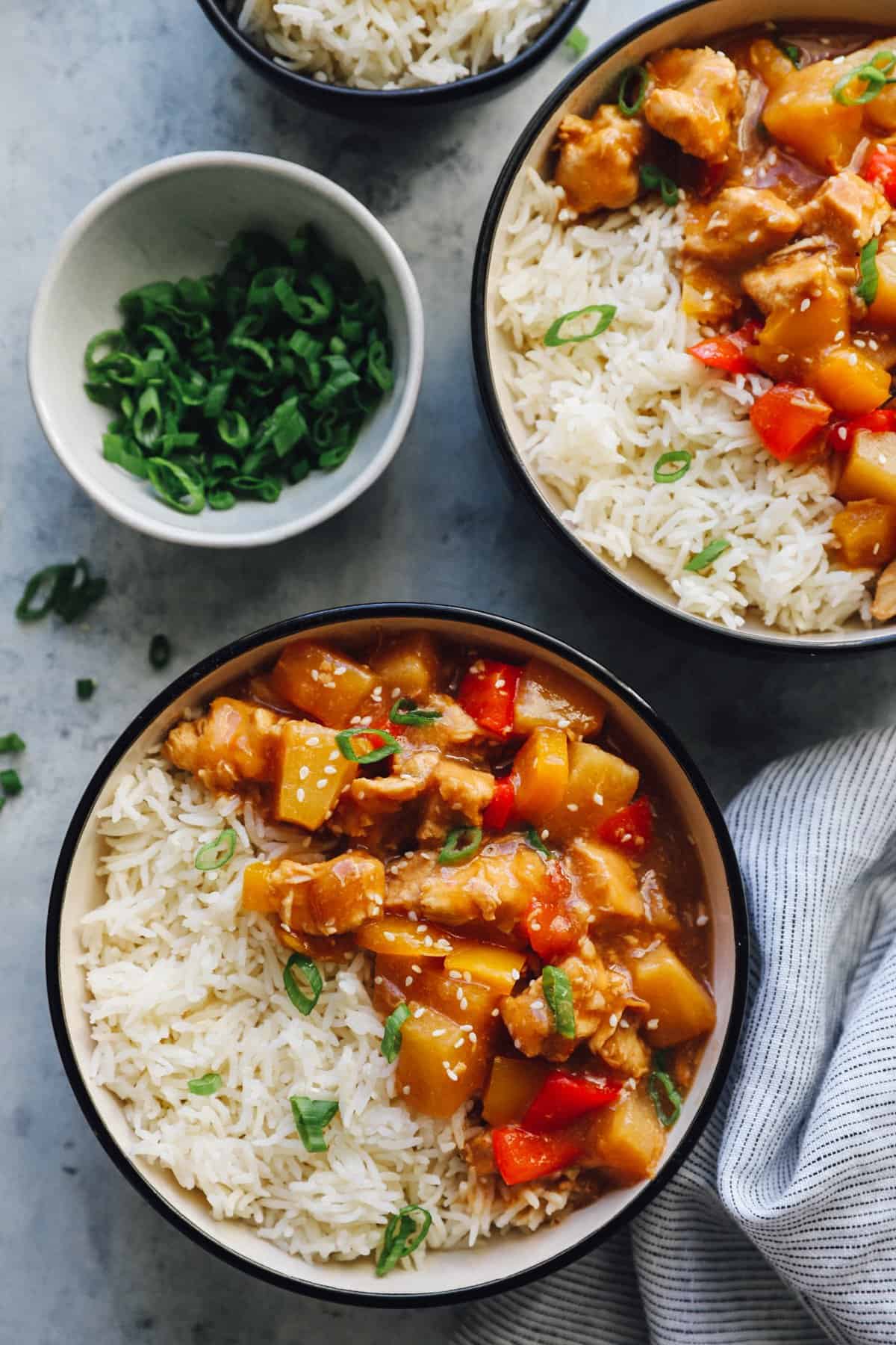 crockpot hawaiian chicken in black and white bowls with rice.