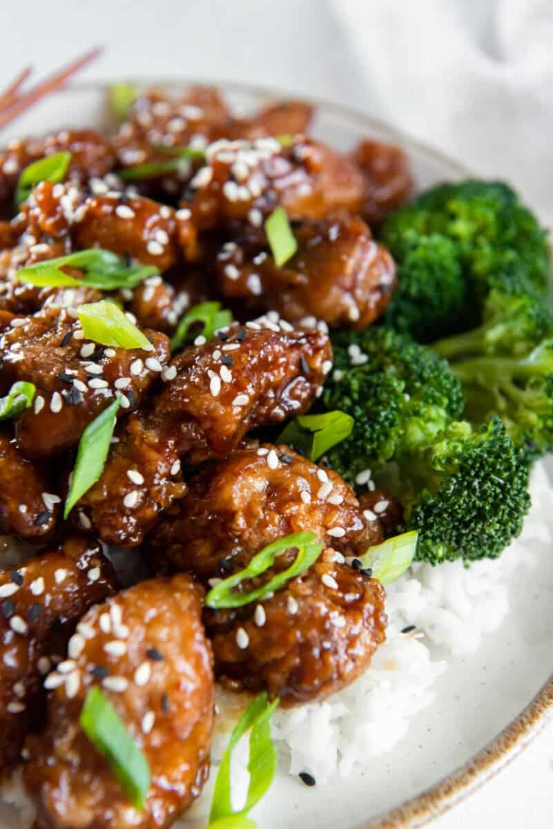 close up of general tsos chicken on a white plate.