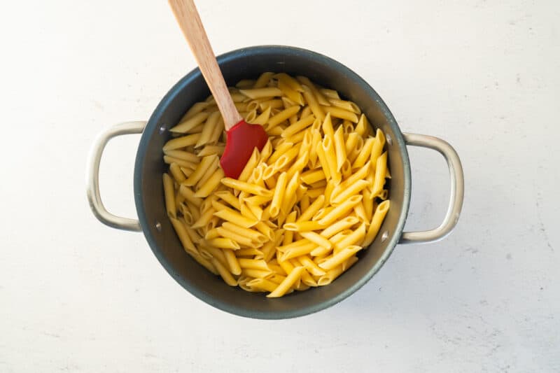 cooked penne in a pasta pot with a rubber spatula.