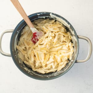sauced mac and cheese in a pasta pot with a rubber spatula.