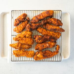 fried chicken tenders on a wire rack set over a baking sheet.
