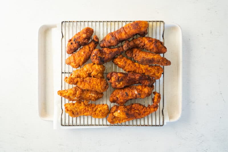 fried chicken tenders on a wire rack set over a baking sheet.