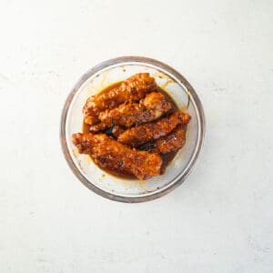 saucy chicken tenders in a glass bowl.