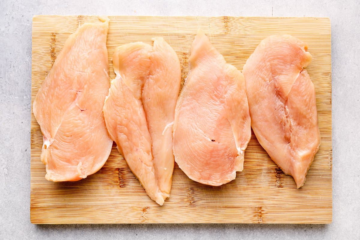 butterflied chicken breasts on a wooden cutting board.