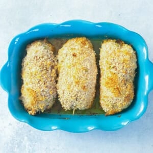 overhead view of 3 baked chicken kievs in a blue baking dish.