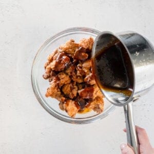 general tsos sauce poured over fried chicken bites in a glass bowl.