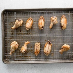 10 baked hot honey chicken wings on a wire rack set in a baking sheet.