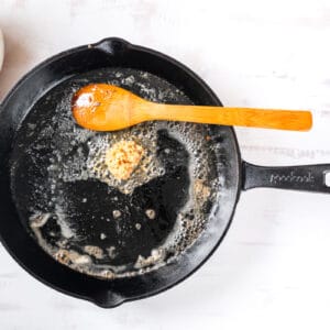 butter and oil sizzling in a skillet with a wooden spoon.
