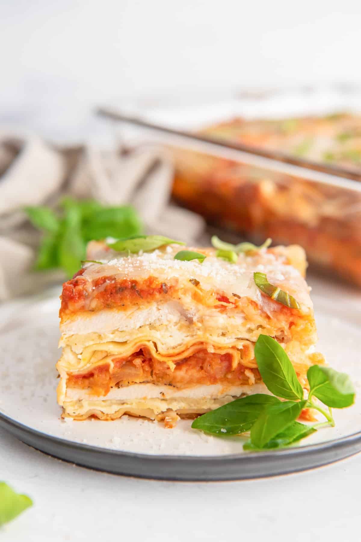 a slice of chicken parmesan lasagna on a white plate.