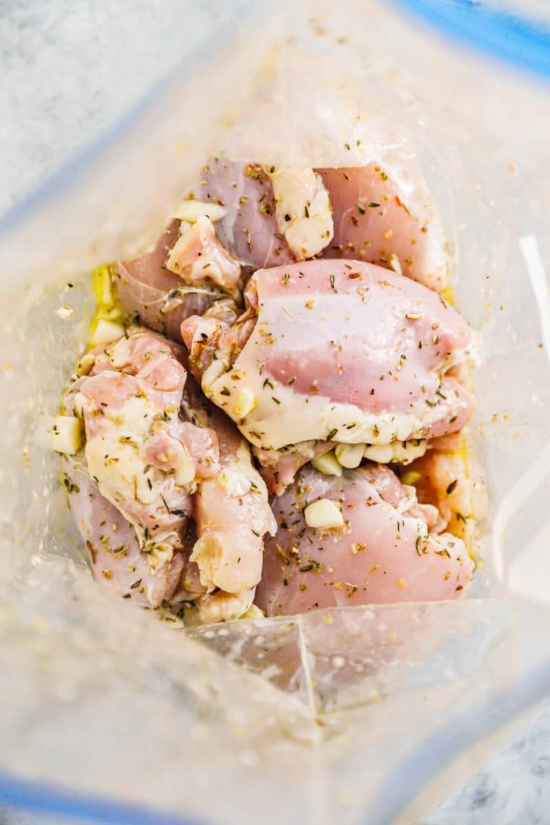 looking into a plastic bag filled with chicken thighs in a greek marinade