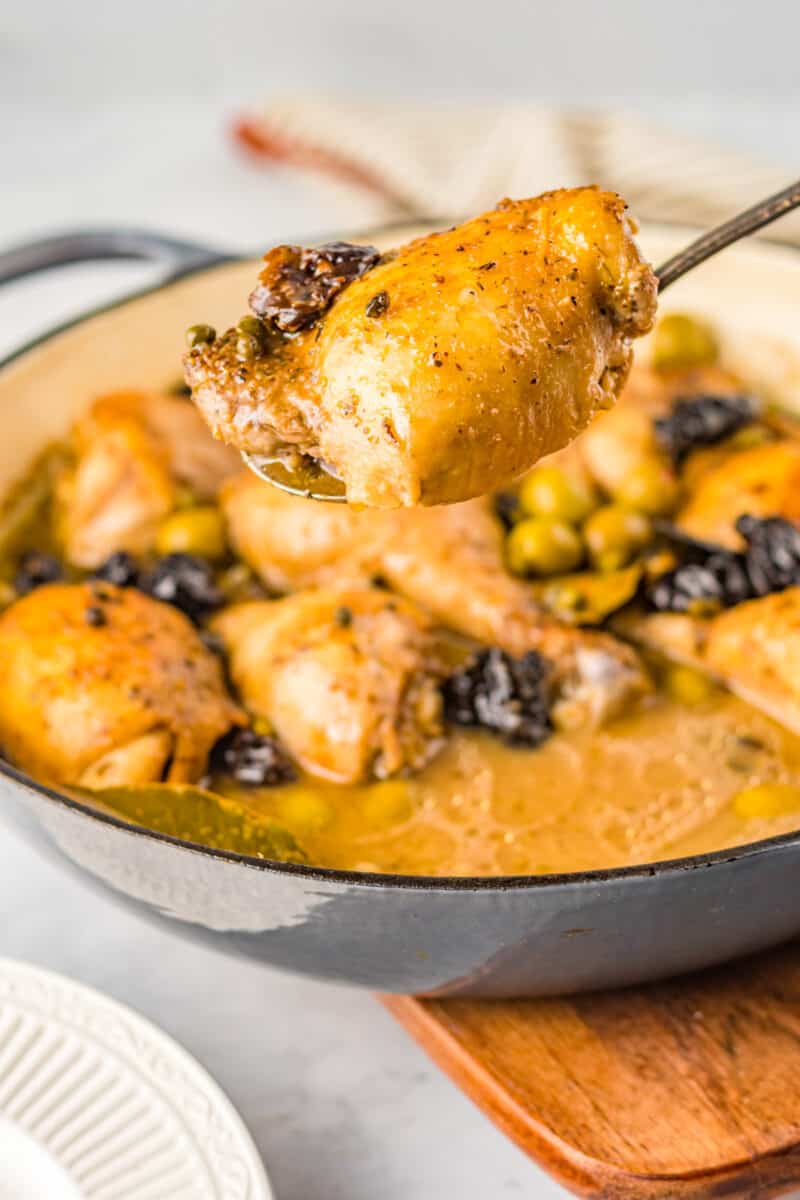 a forkful of chicken marbella suspended above a round pan.