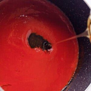 adding honey to hot honey wing sauce in a pan.