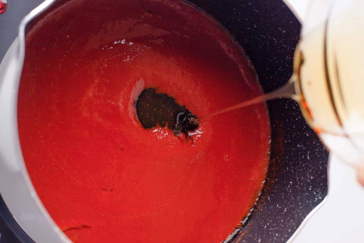 adding honey to hot honey wing sauce in a pan.