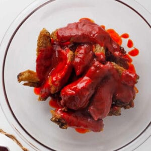 tossing air fried chicken wings with hot honey wing sauce.