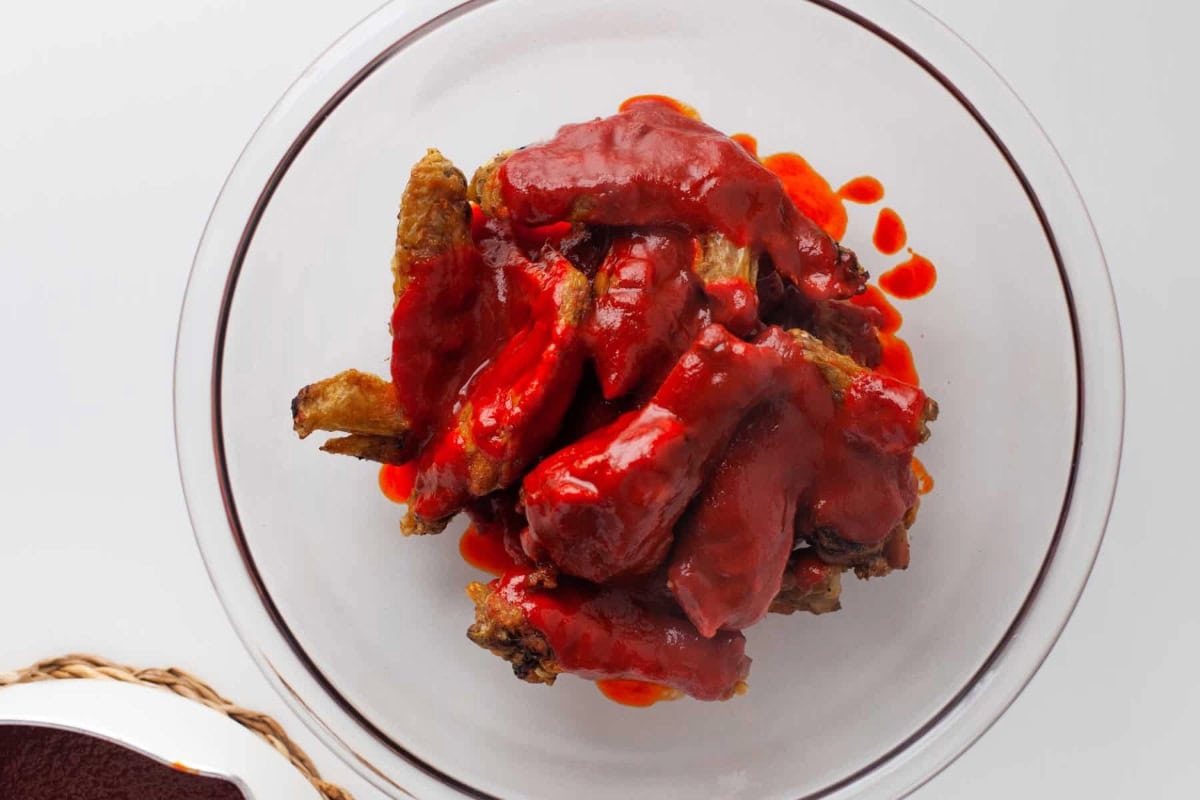 tossing air fried chicken wings with hot honey wing sauce.