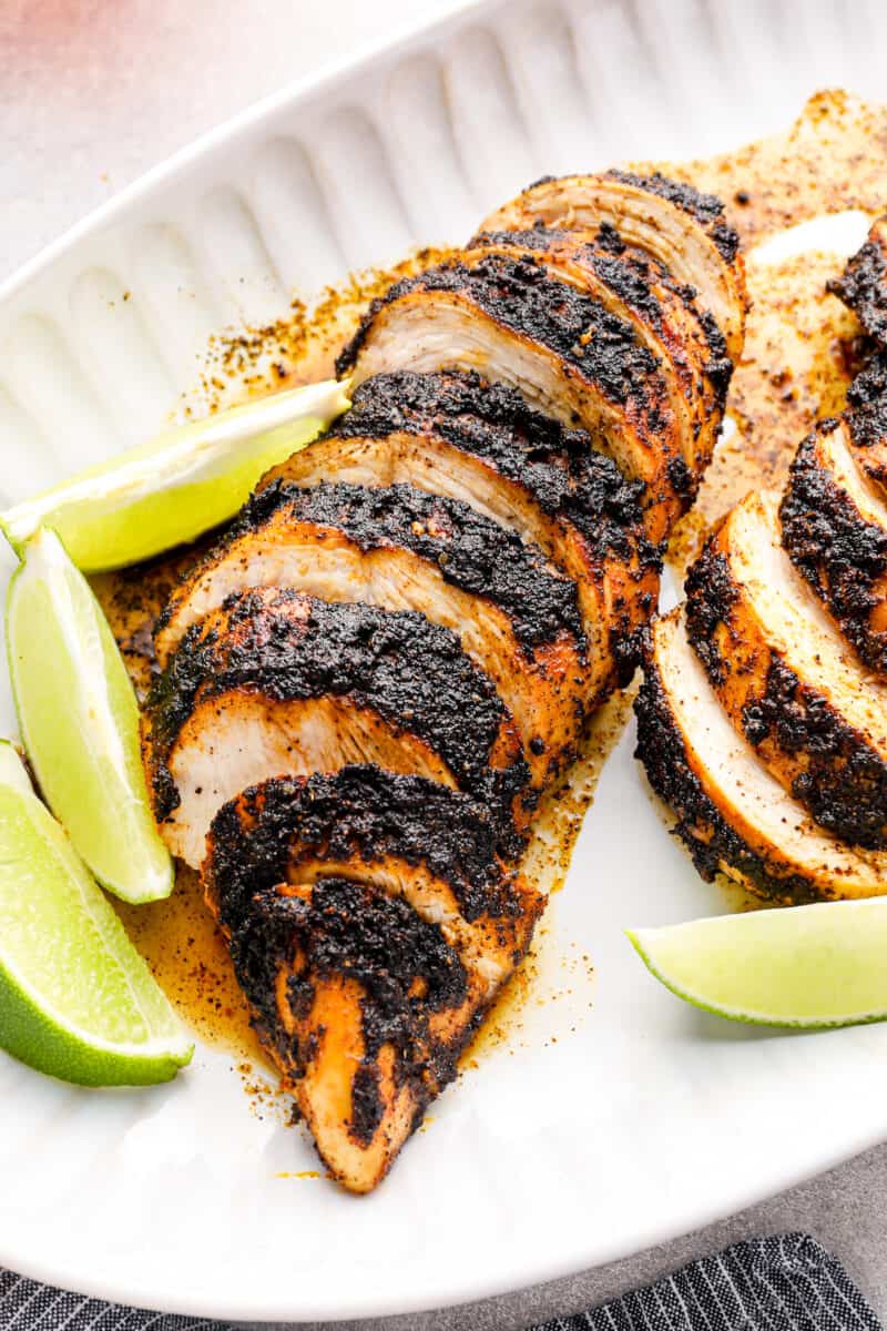blackened chicken on a plate with sliced limes