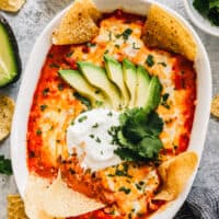 chicken enchilada dip with tortilla chips dipped in
