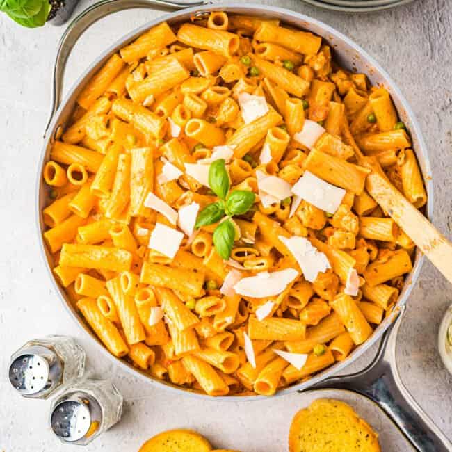 chicken rigatoni in a skillet with basil and a wooden spoon.