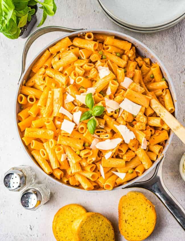 chicken rigatoni in a skillet with basil and a wooden spoon.