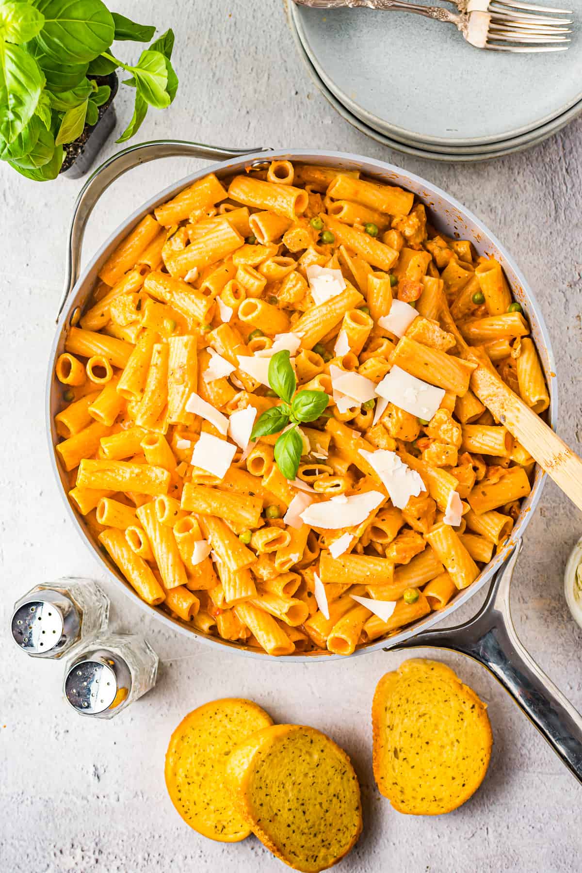 chicken rigatoni in a skillet with basil and a wooden spoon.