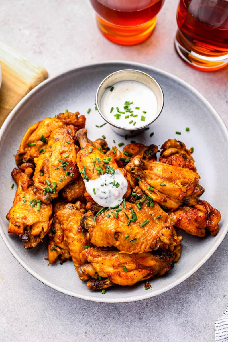 ranch dipped crockpot buffalo chicken wing on a plate of wings.