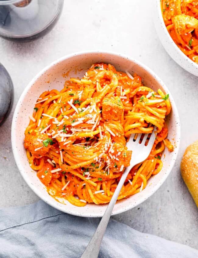 crockpot chicken spaghetti in a white bowl with a fork.