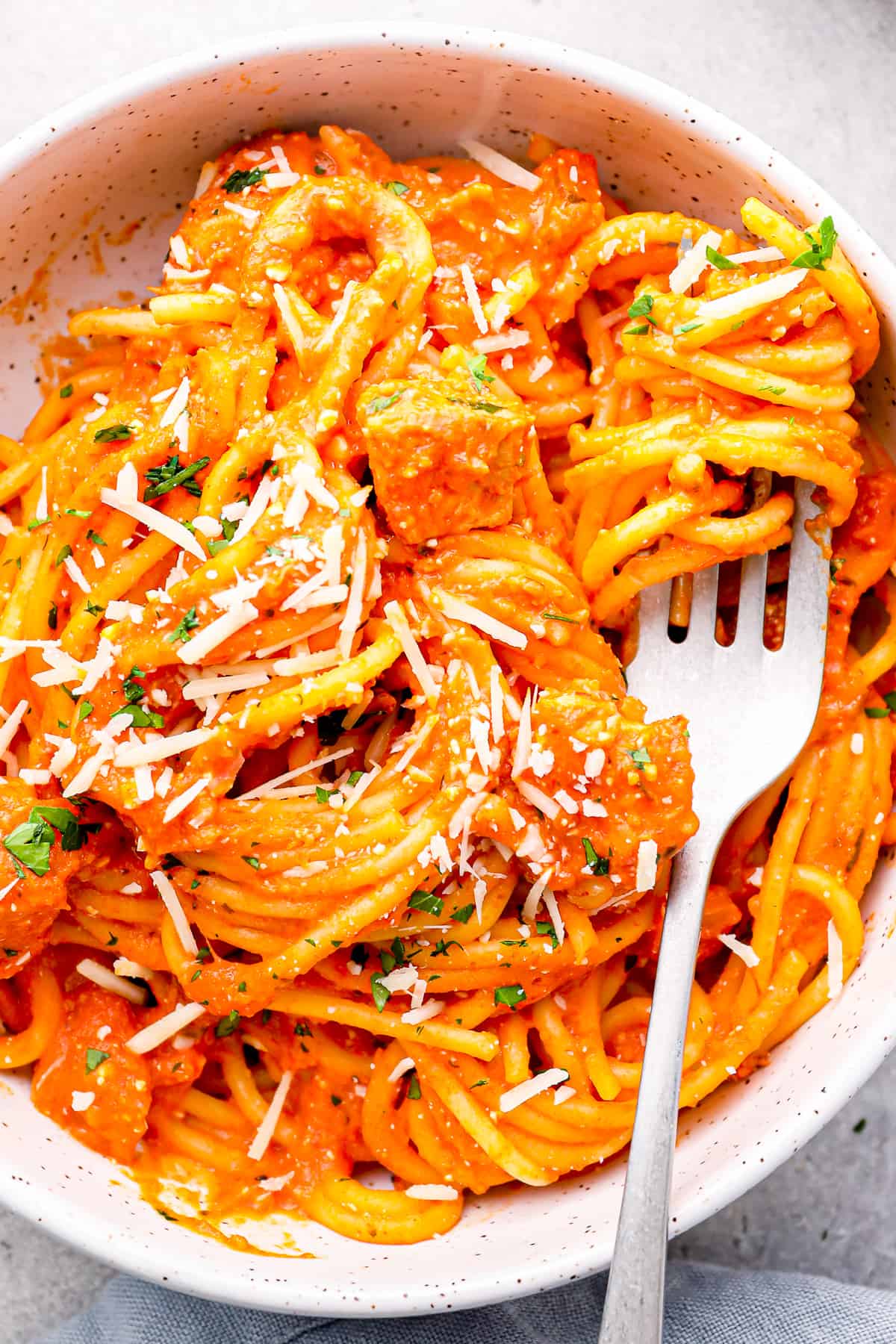 Close up on a bowl of spaghetti with chicken and cheesy marinara sauce.