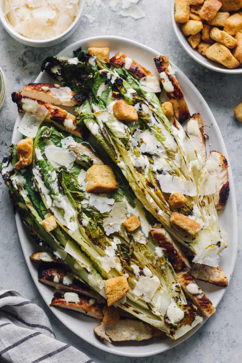 grilled romaine on a plate with grilled chicken, croutons, and dressing