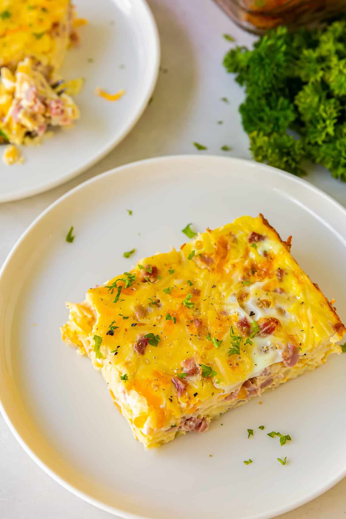 a slice of ham and cheese breakfast casserole on a white plate.
